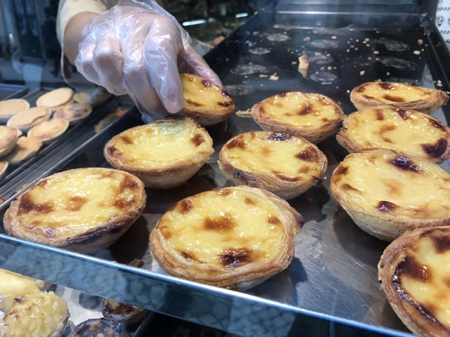 A baker places pastel de nata pastries in the shop window